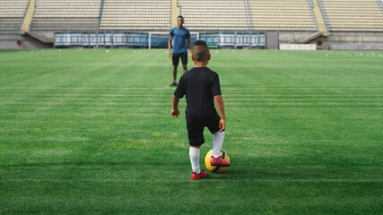 Black father kicking football ball to son