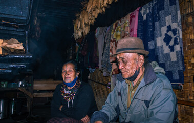 Fototapeta na wymiar apatani tribal couple at their home near fire place cooking food at evening from flat angle