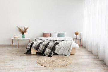 Blog about home interiors and cozy design. Double bed with pillows and blanket, tables with dry plants in vases
