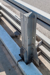 metal roadside fence support with connecting elements and bolts with nuts. Galvanized or metal road barriers. Road safety, protective structures.