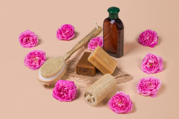 Fototapeta na wymiar Natural soap, loofah loofah and a bottle of cosmetic product on a beige background with roses. Natural organic cosmetics for face and body. Skin care concept