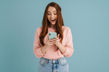 Young ginger woman smiling and using mobile phone