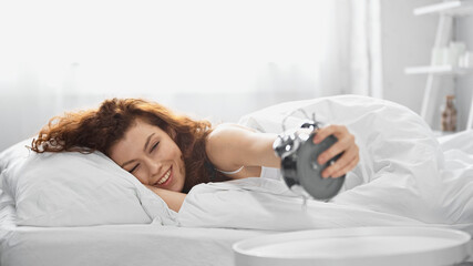 cheerful young woman holding retro alarm clock