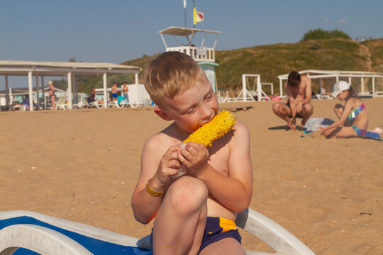 Russian boy on the beach at a Russian resort eating hot corn