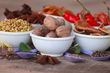 Group of indian spices and herbs difference ware on Wooden teblet,Different spices in spoons on table,Indian bay leaf, Garam masala, Mace, Javitri, Nutmeg, Jaipha