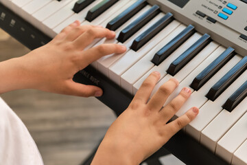 Selective focus of kid's fingers playing the piano.