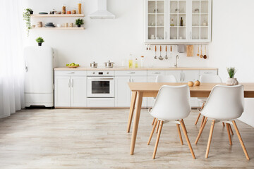 Light kitchen design in scandinavian style. Wooden dining table and white furniture, small refrigerator, empty space