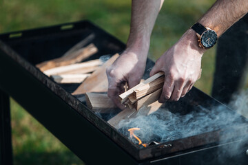Man putting firewood on the grill
