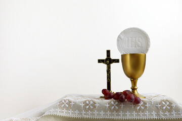 The Feast of Corpus Christi Concept. Holy communion and cup of glass with red wine on table.