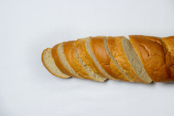 Sliced baguette on a white tablecloth. Bakery product. Delicious bread