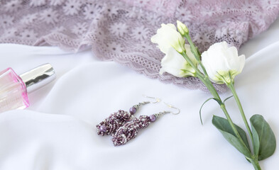 Shopping and fashion concept. Woman elegant lavender lace bra, flowers, jewelry, cosmetics on a white background. Stylish lingerie flat lay.