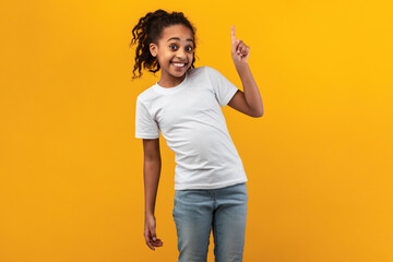 Smiling black girl pointing up at free space