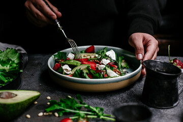 Salad with strawberries, feta, avocado and arugula in a plate on the table. Vegetarian salad