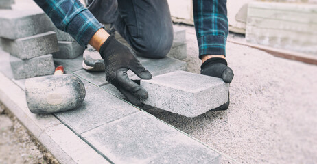 Worker lining paving slabs path