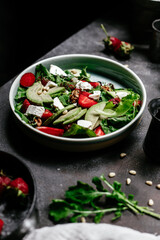 Salad with strawberries, feta, avocado and arugula in a plate on the table. Vegetarian salad
