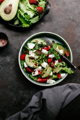 Salad with strawberries, feta, avocado and arugula in a plate on the table. Vegetarian salad
