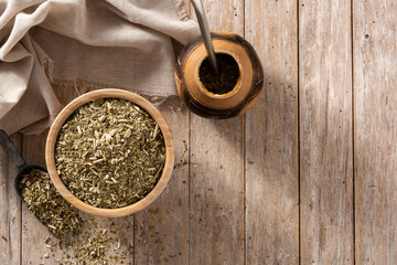 Fototapeta na wymiar Traditional yerba mate tea in bowl on wooden table. typical Argentine drink. Top view. Copy space