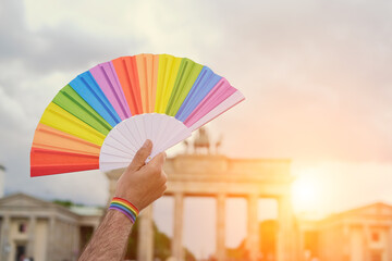 Rainbow fan in hand, symbol of LGBTQIA gay lesbian pride. Rainbow also symbolizes diversity in...