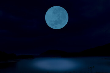 Full moon on sky over lake at night.