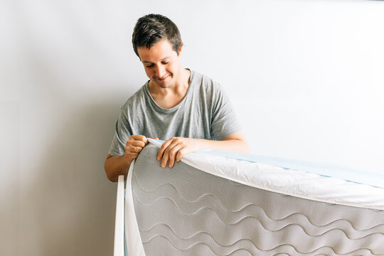 Young adult man preparing the mattress and sheets for his son's crib. concept of arrival of a baby. paternity
