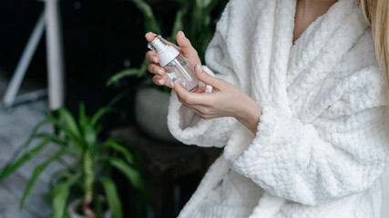 Young woman holding bottle with cosmetics in hands