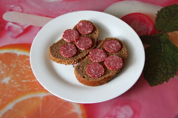 Two black bread sandwiches with salami