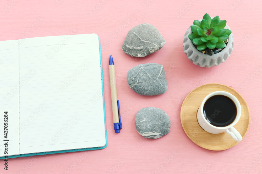 Poster empty open notebook and zen pebbles on pastel wooden background. copy space for text