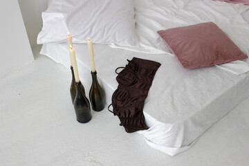 Closeup shot of a white mattress with pillows on floor and three burning candles