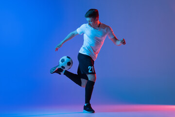 Fototapeta na wymiar One male soccer football player in action and motion isolated on gradient blue pink background in neon light