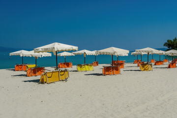 Beach beds under sun umbrellas on an empty sandy beach in Chalkidiki Peninsula, Greece