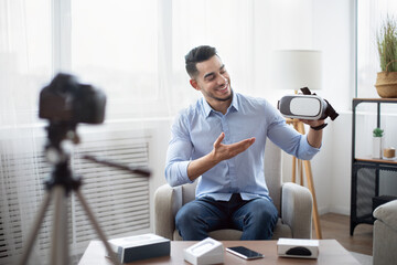 Tech product review. Male vlogger presenting VR headset, recording video about innovative device...