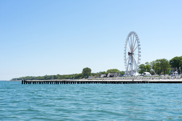 View of the coast from the water, a summer day on the beach with beach chairs, ferris wheel and...