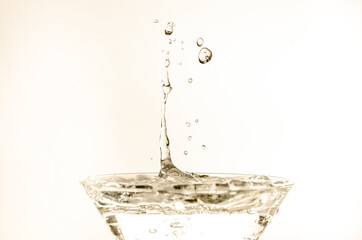 Close-up of water drop falling into a glass on white background