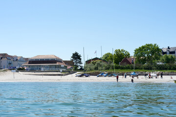 View of the coast from the water, a summer day on the beach with beach chairs, ferris wheel and groynes