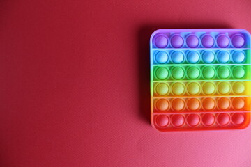 Toy anti-stress popit simple dimple on a red background with a place to stand up text and copyspace