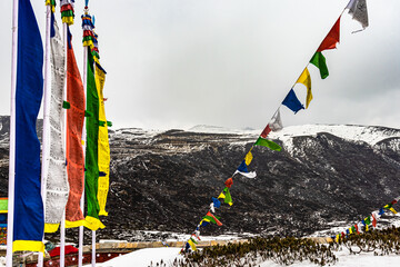 holy buddhist flag at war memorial with snow cap mountains in the background