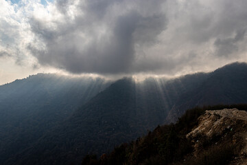 mountain range with sun ray beams and heavy cloud overcast at day