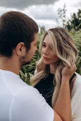 Fototapeta premium Walk a guy and a girl. Love story by the lake in the tall grass. Youth in nature. Summer day.