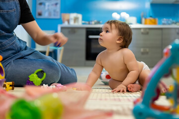 Cute adorable little funny infant caucasian newborn baby sitting on floor and enjoy playing toys...