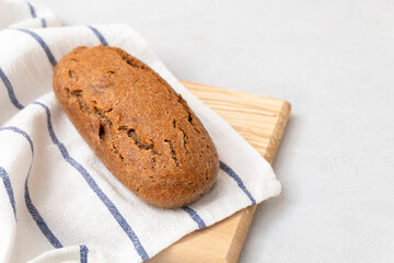 Fototapeta na wymiar Einkorn sourdough bread on cutting board with napkin on neutral grey background with copy space