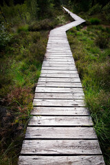 Obraz premium Change course concept: a wooden walkway with a kink or bend over the moor Pietzmoor in northern Germany.