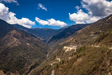 Fototapeta premium mountain valley with curvy road and bright blue sky at sunny day