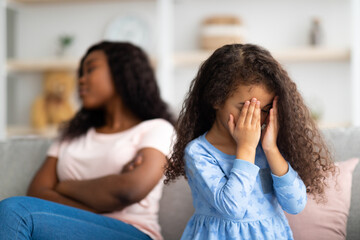 Little black girl crying, having conflict with her angry tired mother at home, free space