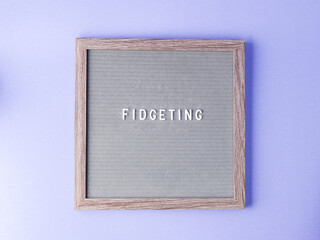 Letter board with word saying Fidgeting on purple