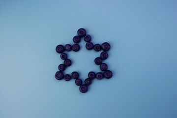 Blueberries are laid out in a star shape. Fresh ripe blueberries on a blue background. 