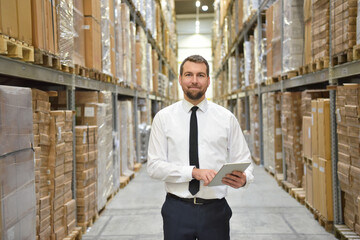portrait friendly businessman/ manager in suit working in the warehouse of a company - control of inventories - obrazy, fototapety, plakaty