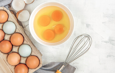 Top view  carton box eggs, egg yolk, whisk, Eggshell on a  wooden background.