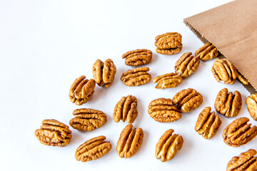Pecan nuts falling from bag on white background.