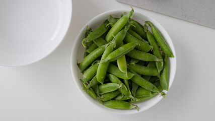 Young peas in a white plate in a white table