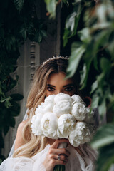 The bride is holding a bouquet of white roses. Portrait of the bride. Beautiful wedding bouquet.